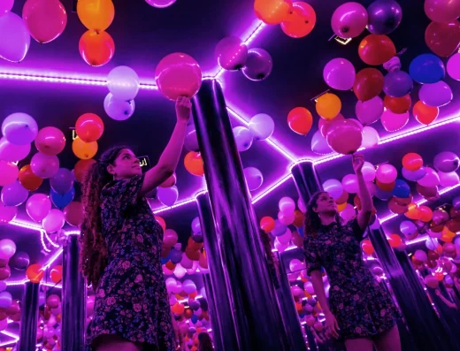 Illuseum Berlin, Infinity Room, woman standing in a room that seems to be infinite, purple, pink balloons