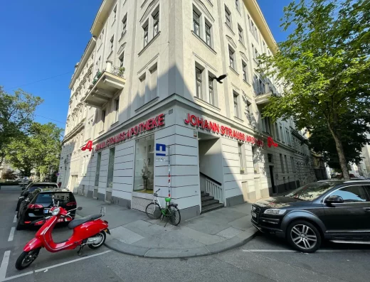 Außenansicht Johann Strauss Apotheke, sonniger Tag, blauer Himmel, Straßenecke